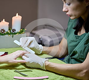 Woman in salon receiving manicure by nail file.