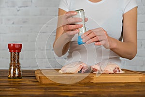 Woman salts the chicken using the grinder