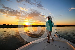Woman Saltwater Fishing Casting From Boat During Sunrise