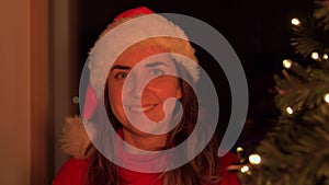 Woman in sana hat over christmas tree at home