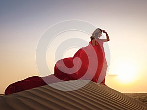 Woman in sands dunes of desert at sunset