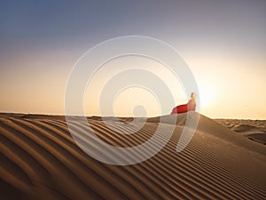 Woman in sands dunes of desert at sunset