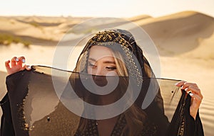 Woman in sands dunes of desert at sunset