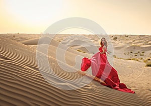 Woman in sands dunes of desert at sunset