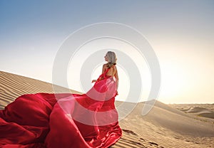 Woman in sands dunes of desert at sunset