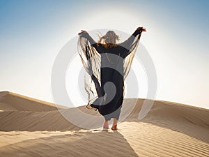 Woman in sands dunes of desert at sunset