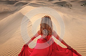 Woman in sands dunes of desert at sunset