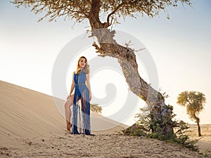 Woman in sands dunes of desert at sunset