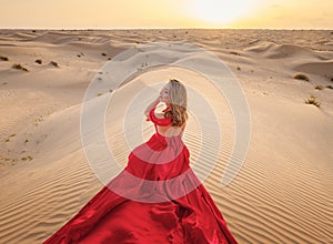 Woman in sands dunes of desert at sunset