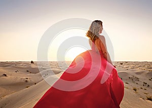 Woman in sands dunes of desert at sunset