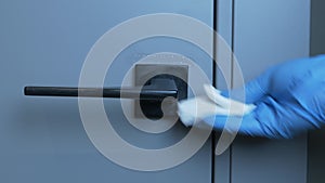 Woman is sanitizing door handle using wet wipe and alcohol sanitizer spray. Female hands are disinfecting and cleaning room to pre