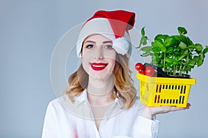 Woman in Santa Claus hat with basket of herbs