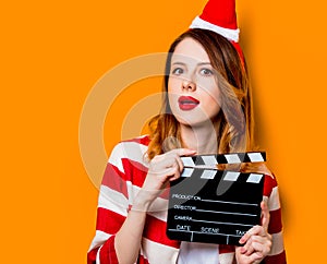 Woman in Santa Claus hat with filmmaking clapperboard