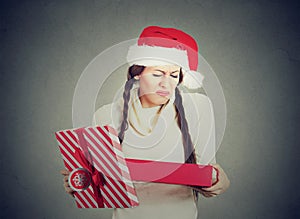 Woman in santa claus hat opening gift upset