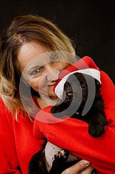 Woman in santa costume and puppy in santa hat