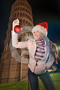 Woman in Santa hat with Christmas ball near Leaning Tower, Pisa