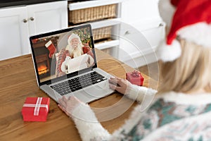 Woman in Santa hat having a video chat with Santa Claus on her laptop at home