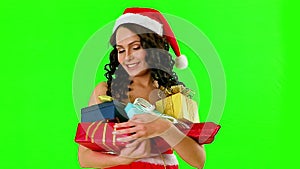 Woman in Santa hat holding gift box. Green background.
