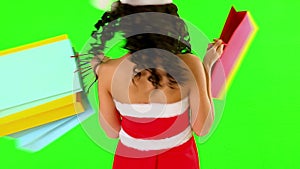 Woman in Santa hat holding shopping bag. Green background.