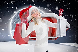 Woman in santa hat holding shopping bags against digitally generated background