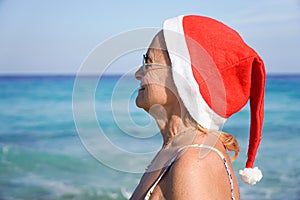 Woman with santa hat looking at the sea. Christmas holiday in summertime