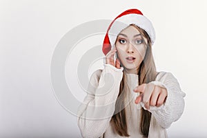 Woman in Santa hat pointing at camera by her finger