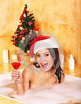 Woman in santa hat relax in bath.