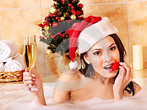 Woman in santa hat relax in bath.