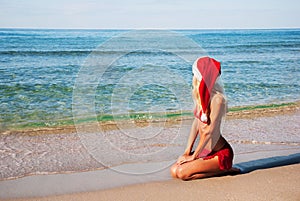 Woman in santa hat on the sea beach.