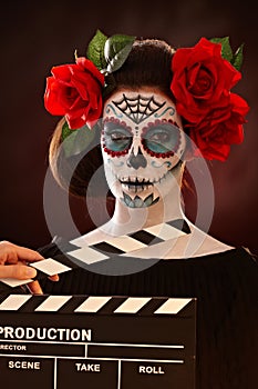 Woman in santa muerte mask behind clapboard