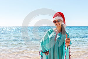 Woman in santa`s hat in bikini at tropical beach. Christmas vacation. copy space