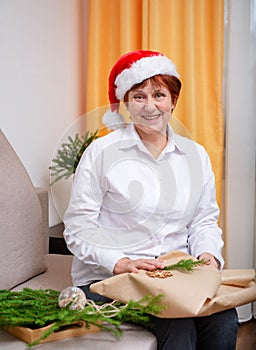 Woman in santa`s hat holding a present and smiling