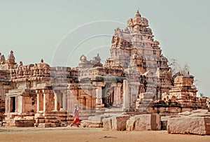 Woman in sari walking past walls of the 7th century Hindu temples, India. Architecture of Pattadakal