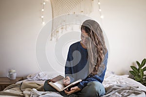 Woman sat on bed writing in her journal