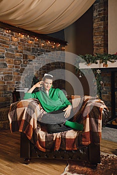 Woman sat comfortably in a wide armchair with a blanket