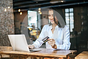 Woman  sat with a laptop and paid with a credit card in a coffee shop