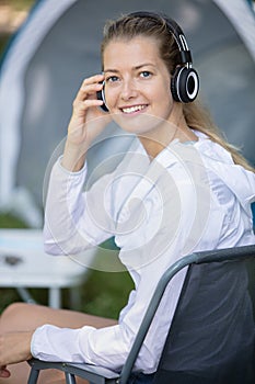 woman sat by tent wearing headphones