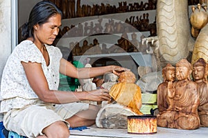 A woman is saturating with stain wooden Buddha