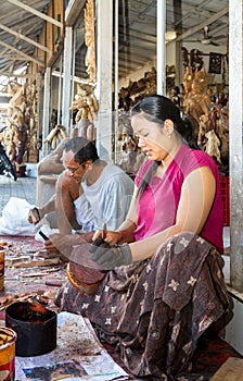 A woman is saturating with stain wooden crafts