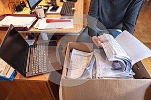 Woman saving and filing company documents in cardboard boxes while teleworking.