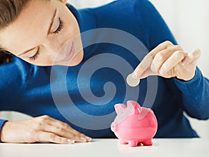 Woman saving money in piggy bank photo