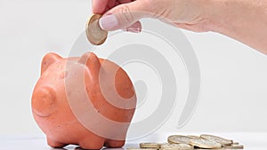 Woman saving money into a traditional clay piggy b