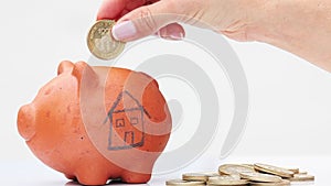 Woman saving money into a traditional clay piggy bank for a house