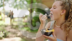Woman savors acai bowl with fresh fruit at tropical garden cafe. Casual, relaxed dining al fresco. Healthy, balanced