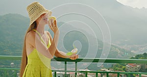 Woman savours a lemon sorbet or ice cream on a balcony. Overlooking the Amalfi coastline in serene sunny summer day.