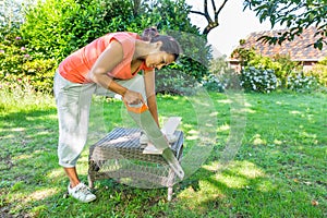 Woman sawing wood outside with handsaw photo