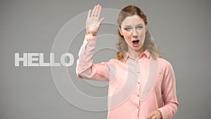 Woman saying hello in sign language, text on background, communication for deaf