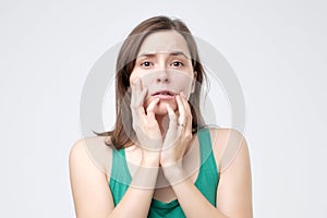 Woman scared ,afraid and anxious biting her finger nails, looking at camera