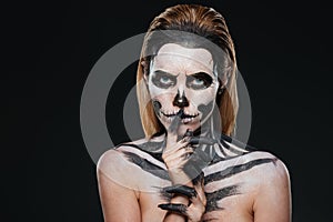 Woman with scared halloween makeup showing silence gesture