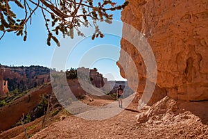 Woman on scenic hiking trail along steep cliffs with view on sandstone rock formations in Bryce Canyon National Park, Utah